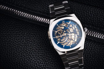 A watch for a businessman. Mechanical steel watch close-up on a leather bag. Business concept