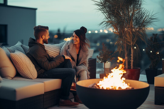Happy couple having a romantic date on outdoor terrace with fire pit in winter