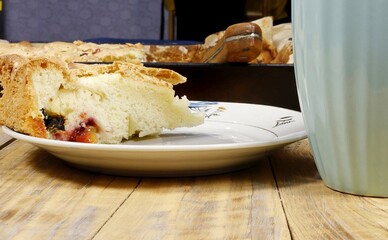 A piece of flan on a plate next to a mug.