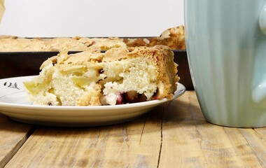 A piece of flan on a plate next to a mug.