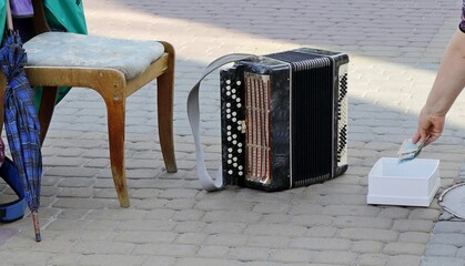 Workplace of a street musician-accordion player. - obrazy, fototapety, plakaty