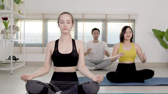 Group of  friend mixed age people making yoga pose in studio. young woman with beautiful athletic body in sportswear doing stretching exercises .