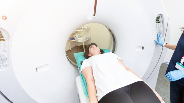 Pretty, young woman goiing through a Computerized Axial Tomography CAT Scan medical test examination in a modern hospital
