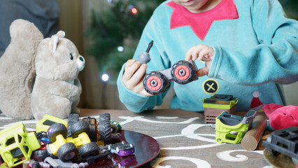 Cute boy elf assembling toys for kids in front of Christmas tree. High quality photo