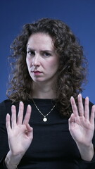Unhappy woman rejecting offer by saying NO with body language, making an X with arms and waving...