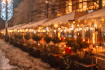 Decorative outdoor string lights at night time. Blurred background of outdoor restaurant with...