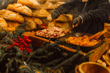 Selling traditional hot fast street food at the Christmas Fair in evening on the central square of the city, the market, the European city for Christmas, Cracow.