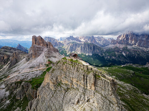 Aerial view of Rifugio Nuvolau, the oldest mountain hut refuge in the Dolomites, Italy. Clouds covering the mountains in the background. Beautiful destinations for hikers and alpinists. Cinematic shot