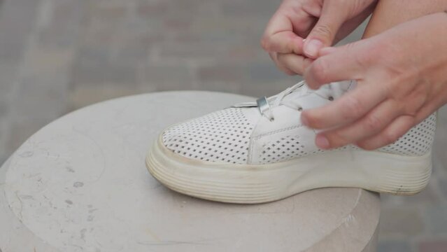 Close-up. women's hands are tying laces on new white sneakers. No logo. 