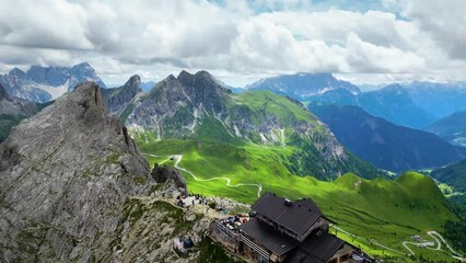 Aerial view of Rifugio Nuvolau, the oldest mountain hut refuge in the Dolomites, Italy. Clouds covering the mountains in the background. Beautiful destinations for hikers and alpinists. Cinematic shot