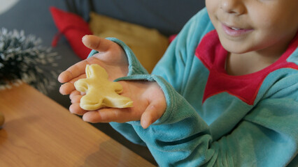 Sweet boy showing gingerbread man cookie that he just cut. Chrismas holidays and happy childhood...