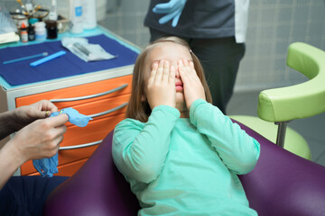 Little scared girl sitting in chair in dentist doctor office. Kid,child afraid of tooth extraction,...
