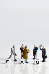 faq word or concept made by white letter cubes on white and gray background, frequently asked questions abbreviation with miniature businessmen figurines having a gathering