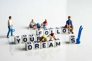 white cubes and miniature leisure figurines with follow your dreams concept, living a meaningful...