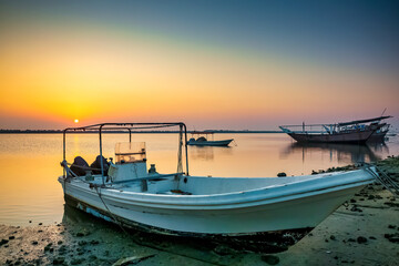 Golden sunrise in Dammam Corniche,Saudi Arabia: Peaceful waters and boats embraced by the morning light.