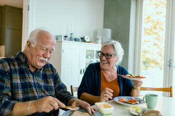 Happy senior couple eating breakfast in kitchen