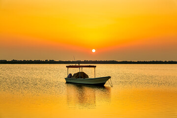 Golden sunrise in Dammam Corniche,Saudi Arabia: Peaceful waters and boats embraced by the morning light.