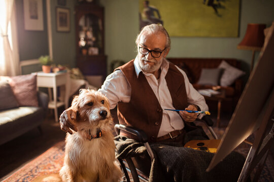 Senior man painting with his dog at home