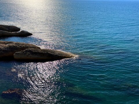 Rocky coast of blue glittering sea.