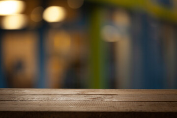 Empty wooden tabletop on blurred light golden bokeh of cafe restaurant bar on empty dark background