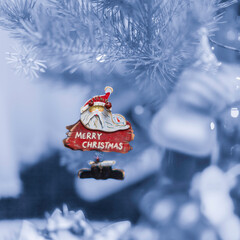 Old handmade wooden toy Santa Claus on the Christmas tree and lights at blurred background.