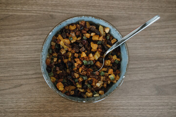 Top view of bowl with raisins and candied fruit with spoon for fruitcake.