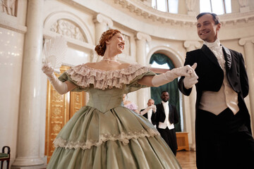 Low angle portrait of beautiful renaissance couple dancing together enjoying ball in palace - obrazy, fototapety, plakaty