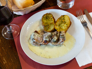 Popular dish of pork with Roquefort cheese sauce with baked potatoes and herbs