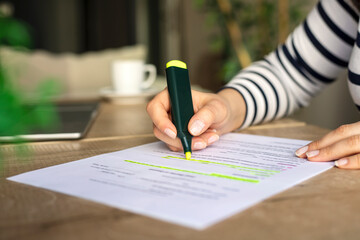 Close up of a woman hand underlining text on document with marker on a desk at home - obrazy, fototapety, plakaty