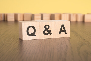 three wooden cubes on a yellow background, with the abbreviation Q and A - Question and Answer
