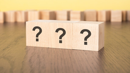 three question marks written on wooden cubes lying on table, business and education concept....