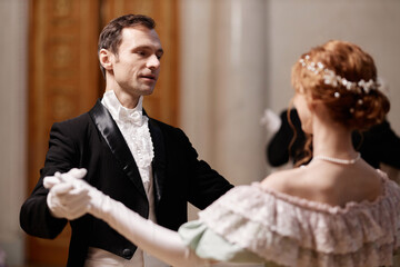 Waist up portrait of classic gentleman dancing waltz with lady in palace ballroom, copy space