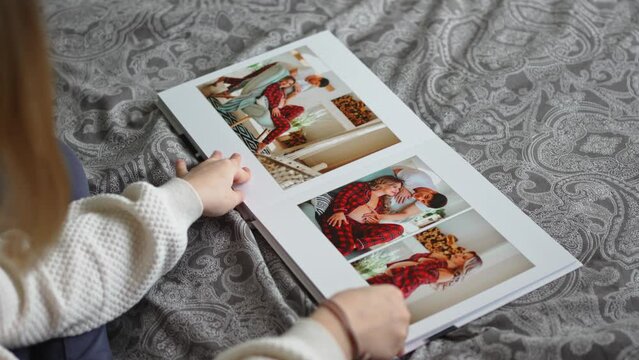 A teen girl flips through a photo book with photos of her dad and pregnant mom.