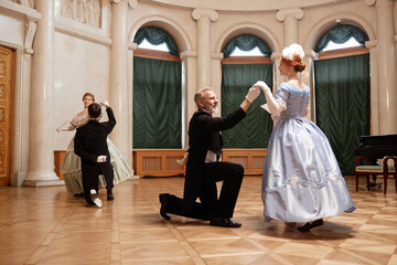 Full length of renaissance couples dancing in palace ballroom with ladies swirling around gentlemen partners, copy space