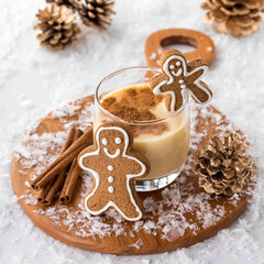 A glass of creamy egg nog and cinnamon surrounded by festive decorations.