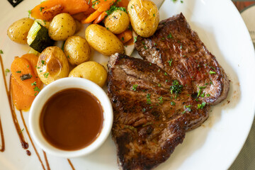 Dish in old bistro in Limoges, France, Limousin cattle beef steak served with oven baked potatos, vegetables and served with light broth or gravy