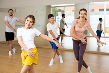 Young girl exercising aerobic dance with her family in gym.