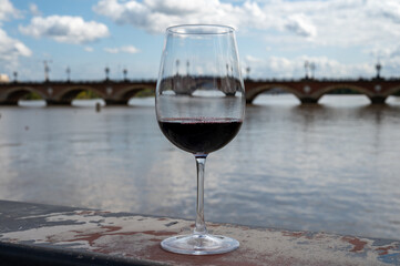 Tasting of Bordeaux blended red wine with wine city Bordeaux on background, left bank of Gironde...