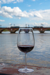 Tasting of Bordeaux blended red wine with wine city Bordeaux on background, left bank of Gironde Estuary, France. Glass of red French wine.