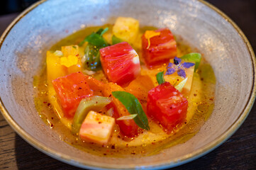 Colorful healthy salad of diced assorted raw French tomatoes served on farm fresh goat’s milk burrata cheese served with vinaigrette dressing