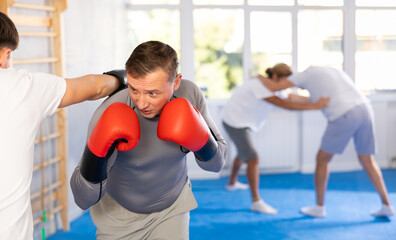 Guy and man sparring partners during training battle fight using technique of boxing match. Boxing section for men, sport as lifestyle - obrazy, fototapety, plakaty