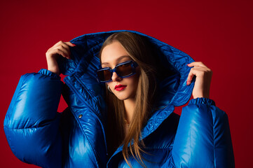 Fashionable confident woman wearing trendy oversized blue puffer down jacket with hood, stylish...