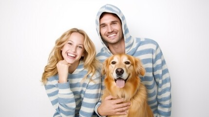 Portrait of happy young couple in pajamas with their beloved golden retriever dog isolated on white background.