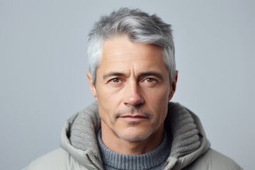Portrait of mature man with grey hair and grey eyes looking at camera.
