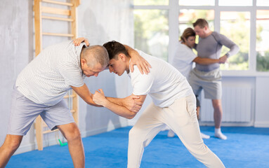 Fototapeta na wymiar Guy and senior man athletes during classes, training improve and practice wrestling with opponent in technique of martial arts. Work on yourself, increase endurance, determination, courage