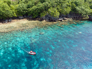 A healthy coral reef fringes a lush, tropical island near Ambon, Indonesia. This remote, tropical area harbors extraordinary marine biodiversity.