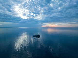 A phinisi schooner, used as a diving live aboard, drifts in calm seas at sunrise near Ambon, Indonesia. This beautiful area harbors extraordinary marine biodiversity.