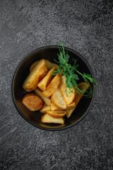 Potato wedges roasted in the oven in a dark plate