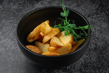 Potato wedges roasted in the oven in a dark plate