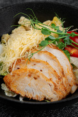 Salad with roasted chicken breast sliced in layers, quail egg, cherry tomatoes and grated parmesan cheese